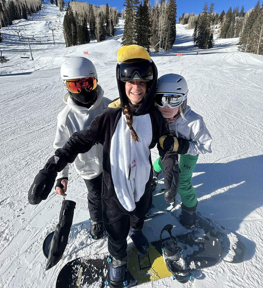 3 young snowboarders posing together on a ski slope