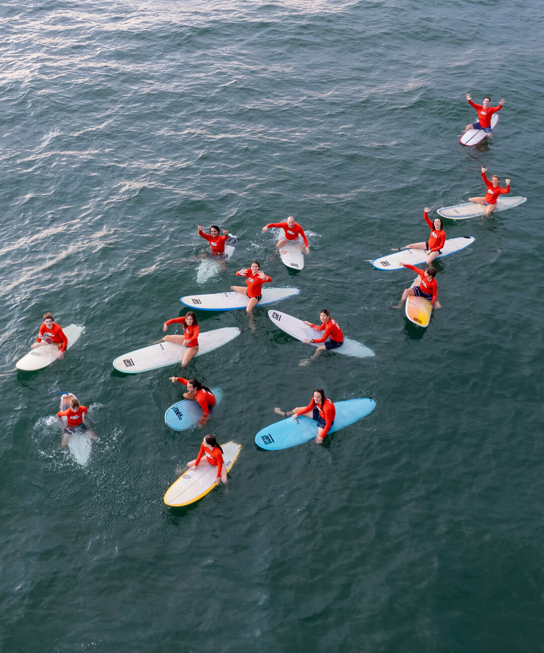 Surf & Service students pose together on their surfboards in the water