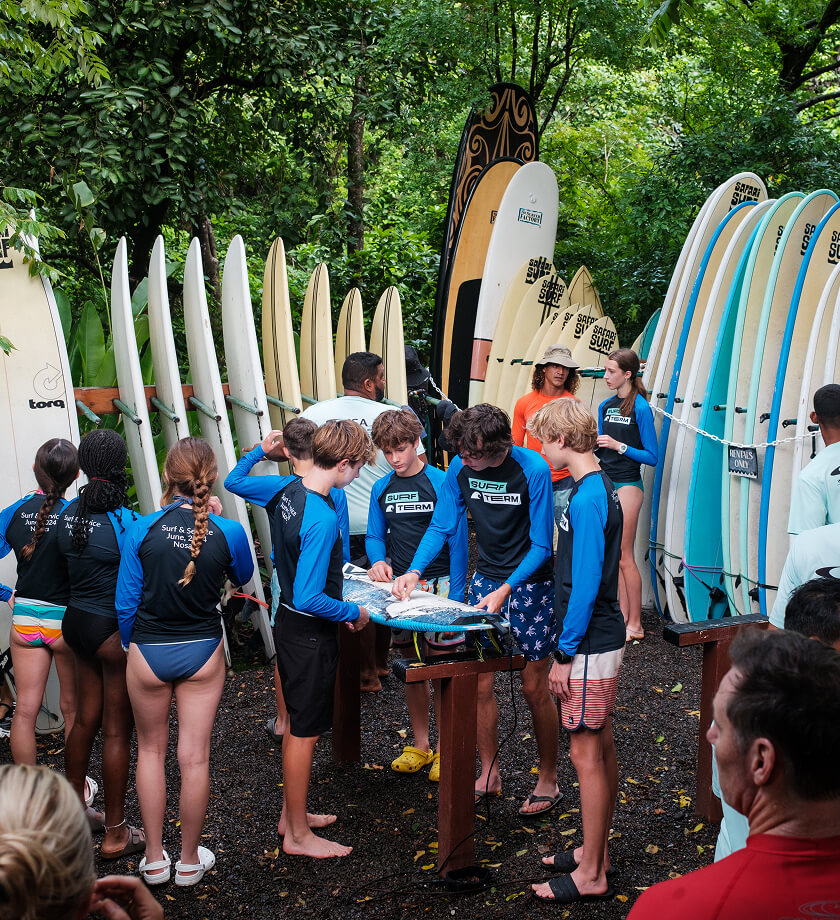 A group of Surf Term students waxing surfboards