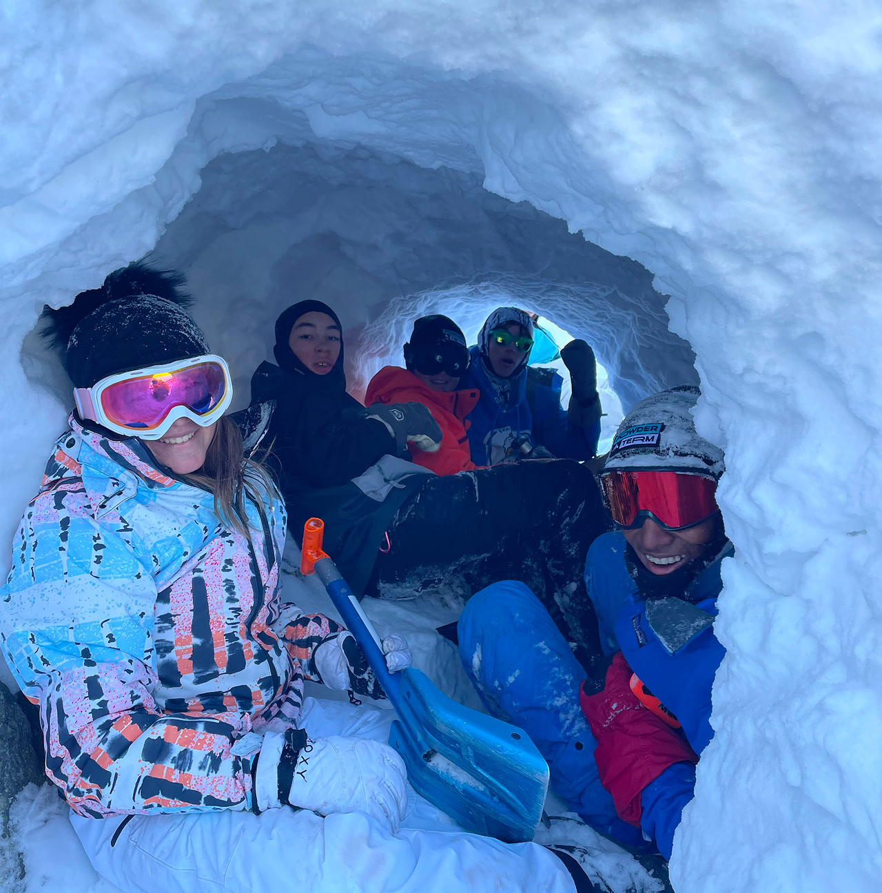 5 people hang out together in a snow dugout
