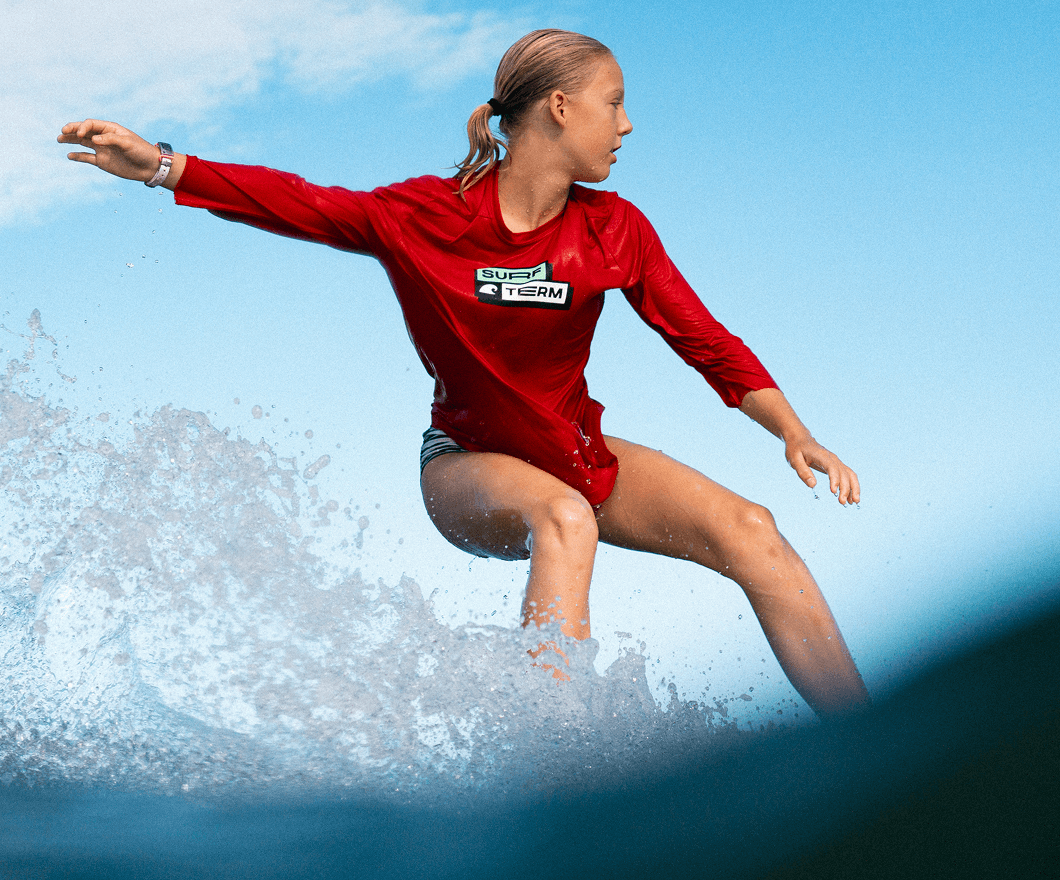 A Surf Term student rides a wave with her arm up