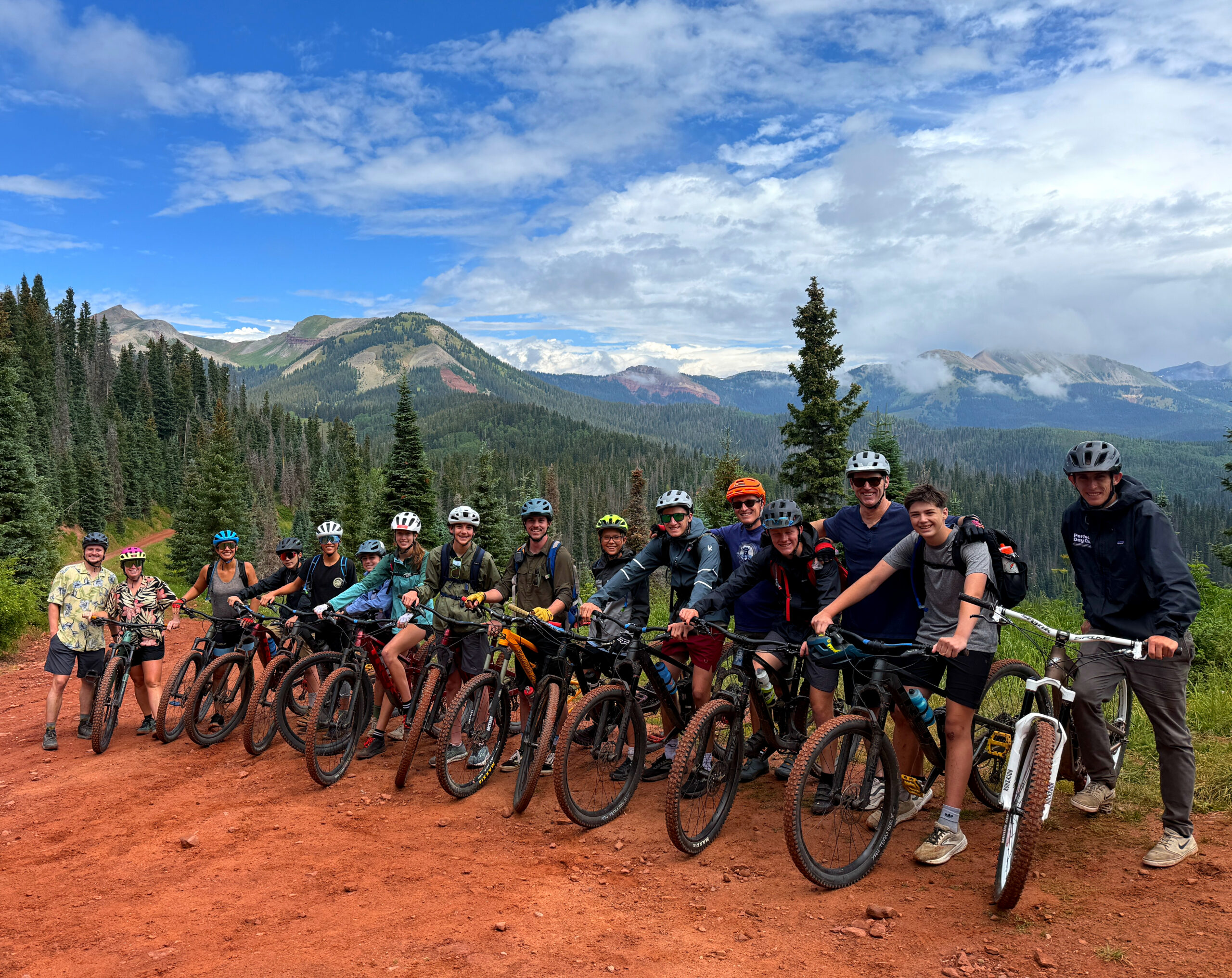 A group of teens pausing for a photo while biking on a mountain trail.