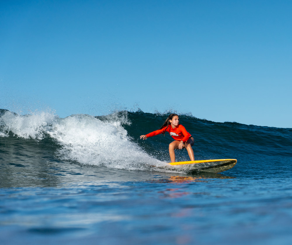 Teen learning to surf and riding a wave
